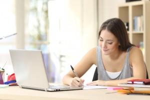 female student studying online and making notes