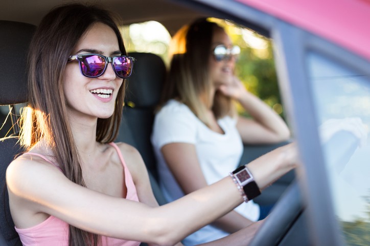 two young women driving a car in the summer