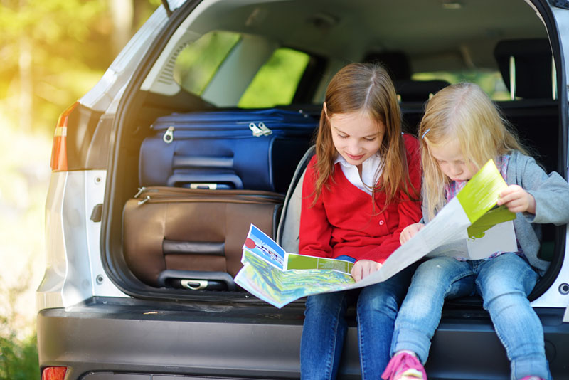Children using a map in the back of a car