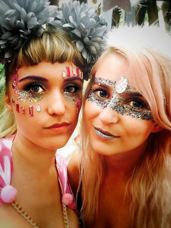 Two women at a festival with face jewels and glitter