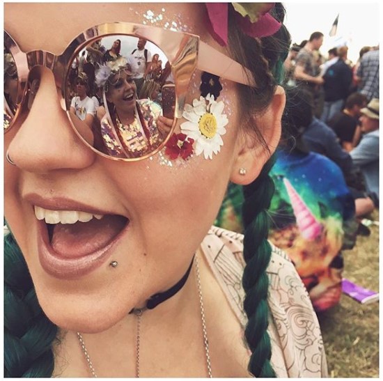 Smiling woman with copper sunglasses and pressed daisies on her cheeks