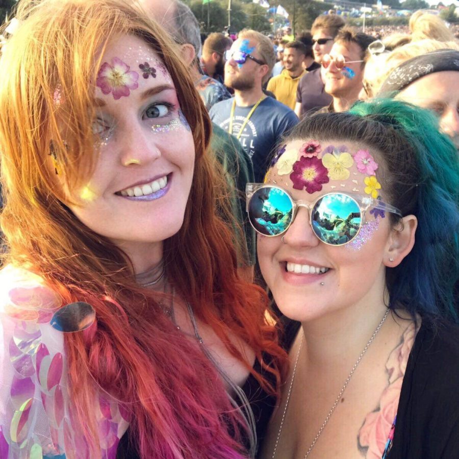 Two women at a festival with pressed flower face decorations