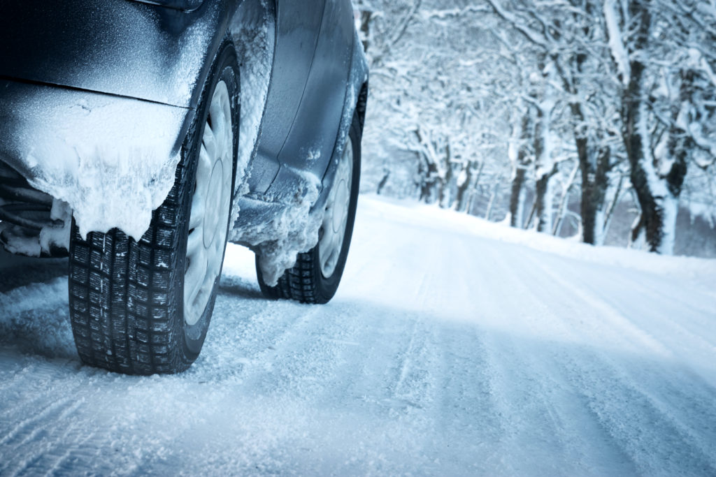 Car tires on winter road covered with snow